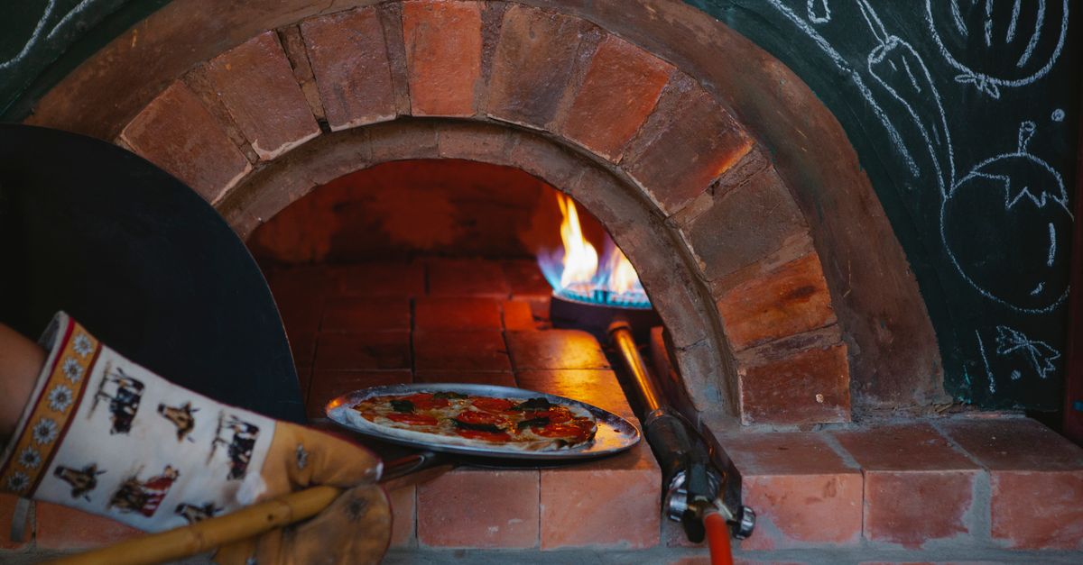 Quanto guadagna una pizzeria — forno a legna con pizze in cottura